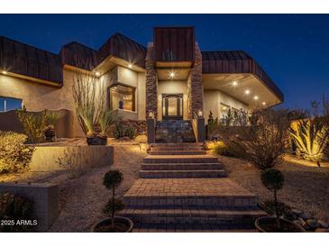 Stunning nighttime view of a luxury home with stone accents and landscape lighting at 11501 E Mark Ln, Scottsdale, AZ 85262