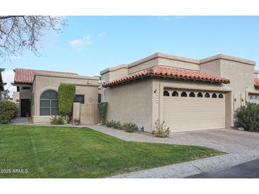 Tan stucco home with tile roof, 2-car garage, and landscaped lawn at 4116 E Sunnyside Dr, Phoenix, AZ 85028