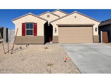 One-story house with tan siding, red shutters, and a two-car garage at 23256 W Miami St, Buckeye, AZ 85326