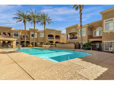 Stunning community pool surrounded by palm trees and well-maintained buildings on a clear day at 8245 E Bell Rd # 142, Scottsdale, AZ 85260