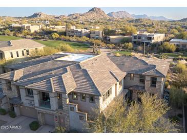 Gorgeous aerial view of a multi-story home showcasing tile roof, stone accents, desert landscaping, and a mountain backdrop at 10260 E White Feather Ln # 1038, Scottsdale, AZ 85262