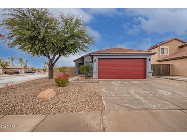 Single-story home with red garage door and landscaped front yard at 14805 W Caribbean Ln, Surprise, AZ 85379