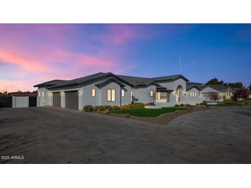 Stunning exterior view of home with lush landscaping, stone driveway, and beautiful contemporary architecture at sunset at 24540 S 190Th Ct, Queen Creek, AZ 85142