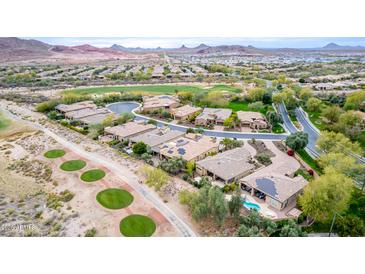 Panoramic aerial view of a golf course community featuring well-manicured lawns, mature trees, and a stunning mountain backdrop at 28247 N 128Th Dr, Peoria, AZ 85383