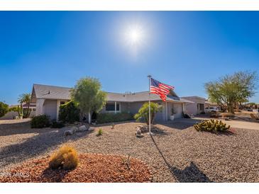 Charming home featuring desert landscaping, a well-maintained yard, and a prominent American flag at 12439 W Eveningside Dr, Sun City West, AZ 85375