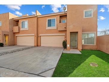 Tan two-story townhome with two-car garage and grassy yard at 3703 E Mitchell Dr, Phoenix, AZ 85018