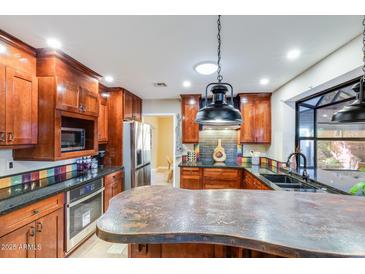 Stunning kitchen boasts custom cabinets, stainless steel appliances, granite counters, and unique backsplash at 6720 E Phelps Rd, Scottsdale, AZ 85254
