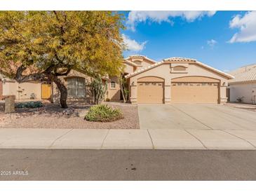 Tan house with three-car garage and landscaped yard at 20967 N 96Th Ln, Peoria, AZ 85382