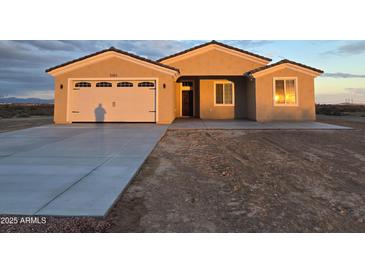 Tan house with a three-car garage and desert landscaping at 5403 S 360 Th Ave, Tonopah, AZ 85354