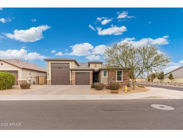 Two-story house with stone and stucco exterior, two-car garage, and landscaping at 7718 W Raymond St, Phoenix, AZ 85043