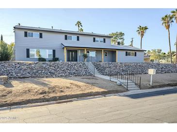 Two-story house with gray siding, stone wall, and a wood-framed entryway at 925 W Fairway Dr, Mesa, AZ 85201