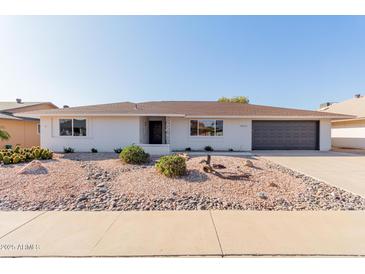 House exterior with a dark garage door and landscaping at 13223 W Gaucho Dr, Sun City West, AZ 85375