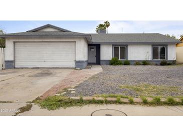 Charming single-story home with a two-car garage, gravel yard, and a welcoming front entrance at 13804 N 52Nd Dr, Glendale, AZ 85306