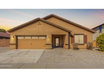 Tan house with a two-car garage, landscaping, and a front walkway at 25360 W Fremont Ct, Buckeye, AZ 85326