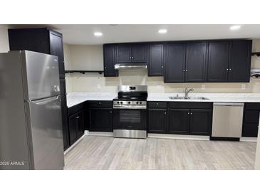 A renovated kitchen with stainless steel appliances, white countertops, and dark cabinetry stands ready for a new owner at 1983 E Don Carlos Ave, Tempe, AZ 85281