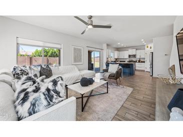 Bright living room with white sofa, ceiling fan, marble coffee table, and access to the kitchen at 2776 E Mews Rd, Gilbert, AZ 85298