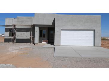 New stucco home featuring a white garage door and covered porch awaiting final construction touches at 28583 N 257Th Dr, Wittmann, AZ 85361
