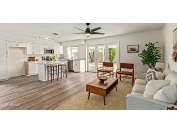 Open concept kitchen and living area with island, stainless steel appliances, and wood-look flooring at 3701 W Evans Dr, Phoenix, AZ 85053