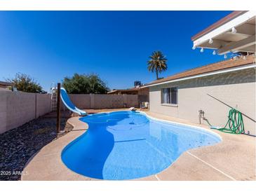 Inviting kidney-shaped swimming pool with a slide in the backyard, perfect for summer fun at 3701 W Evans Dr, Phoenix, AZ 85053