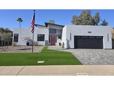 Modern home with red front door, landscaped lawn, and paved driveway at 14426 N 39Th Way, Phoenix, AZ 85032