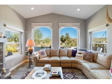 Bright living room featuring large windows with desert views, vaulted ceilings, and a comfortable, curved sectional sofa at 17318 E Quail Ridge Dr, Fountain Hills, AZ 85268