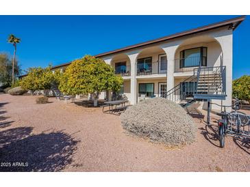 Exterior view of a two-story building with balconies, landscaping, and a stairway at 3270 S Goldfield Rd # 816, Apache Junction, AZ 85119