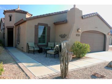 Tan house with brown garage door, sitting area, and desert landscaping at 9219 S 185Th Ave, Goodyear, AZ 85338