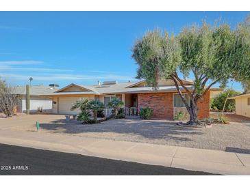 Brick ranch house with a two-car garage and nicely landscaped front yard at 13226 W Mesa Verde Dr, Sun City West, AZ 85375