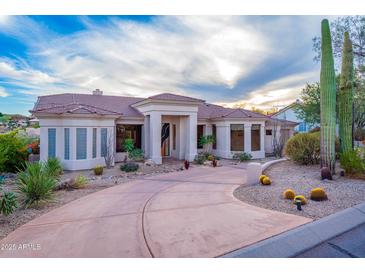 Expansive desert home boasting a circular drive and elegant columns framing the entrance and lush, native landscaping at 15701 E Greystone Dr, Fountain Hills, AZ 85268