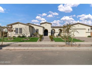 Stunning single-story home with manicured lawn, decorative stone and a welcoming arched entryway at 20456 E Camina Buena Vis, Queen Creek, AZ 85142