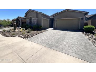 Charming home featuring a two-car garage, attractive brick driveway, and desert landscaping in a warm, sunny setting at 23448 N 76Th Pl, Scottsdale, AZ 85255