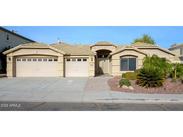 House exterior featuring a three-car garage and well-manicured landscaping at 29606 N 21 Dr, Phoenix, AZ 85085