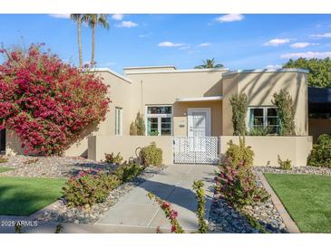 Cute stucco home with landscaped front yard, walkway, and white gate at 320 W Cypress St, Phoenix, AZ 85003