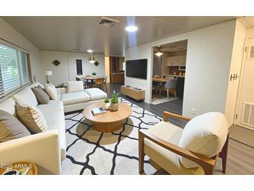 Comfortable living room featuring a white couch, round coffee table, and a graphic rug, with views of the dining area at 8103 E Southern Ave # 84, Mesa, AZ 85209