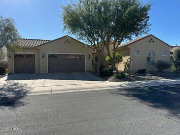 Tan two-story house with a three-car garage and landscaped yard at 27071 W Marco Polo Rd, Buckeye, AZ 85396