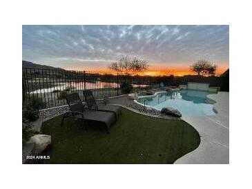 Stunning sunset view over a tranquil lake and inviting pool area at 41717 N Moss Springs Ct, Anthem, AZ 85086