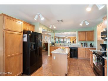 Spacious kitchen with granite island, stainless steel appliances, and light wood cabinets at 43322 W Blazen Trl, Maricopa, AZ 85138