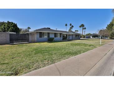 Charming single-story home with a lush green lawn and mature palm trees offering nice curb appeal at 811 W Northern Ave, Phoenix, AZ 85021