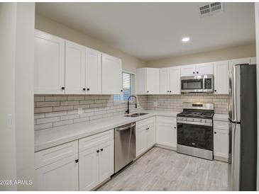 Modern kitchen with white cabinets, stainless steel appliances, and quartz countertops at 849 W Mitchell Dr, Phoenix, AZ 85013