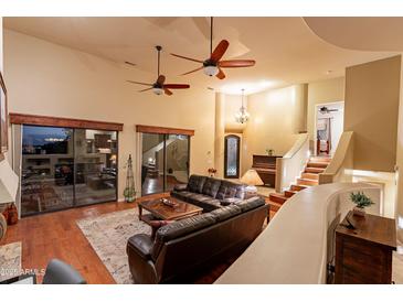 Open-concept living room with hardwood floors, ceiling fans, and staircase to the second floor at 15302 E Lotus Ln, Fountain Hills, AZ 85268