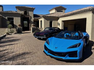 A beige stucco home with a beautiful brick driveway showing off classic and modern sports cars at 3254 N Ladera Cir, Mesa, AZ 85207