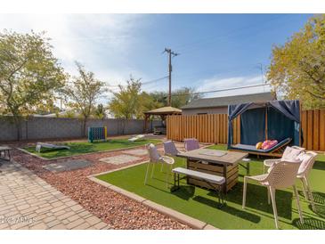 A spacious backyard with a covered lounge area, artificial turf, and fun yard games for outdoor enjoyment at 3132 N 15Th Ave, Phoenix, AZ 85015