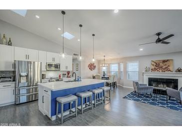 Bright open kitchen with stainless appliances, white cabinetry, pendant lights and island with seating, flowing into the living space at 5507 E Grandview Rd, Scottsdale, AZ 85254