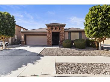 Charming single-story home featuring stone accents, a two-car garage, and manicured landscaping at 676 N 156Th Ln, Goodyear, AZ 85338