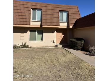 Tan brick condo with brown tile roof, landscaping, and walkway at 1631 E Dunbar Dr, Tempe, AZ 85282