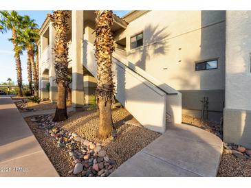 A building exterior with palm trees, rock landscaping, a sidewalk, and outdoor stairs to the second level at 10401 N Saguaro Blvd # 210, Fountain Hills, AZ 85268