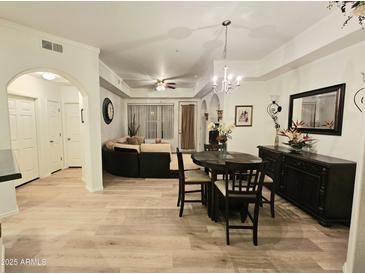 Bright, open-concept living room with light wood floors and elegant chandelier at 14575 W Mountain View Blvd # 11210, Surprise, AZ 85374