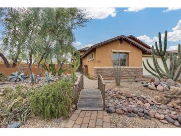 Charming home with xeriscaped front yard, featuring a wooden footbridge and various cacti at 11259 W Harrison St, Avondale, AZ 85323