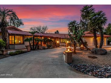 Beautiful desert home exterior at sunset, showcasing a large driveway and landscaping at 22206 N La Senda Dr, Scottsdale, AZ 85255