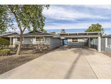 Charming single-story home featuring a covered carport, a stone accent wall, and mature landscaping at 7018 E Wilshire Dr, Scottsdale, AZ 85257